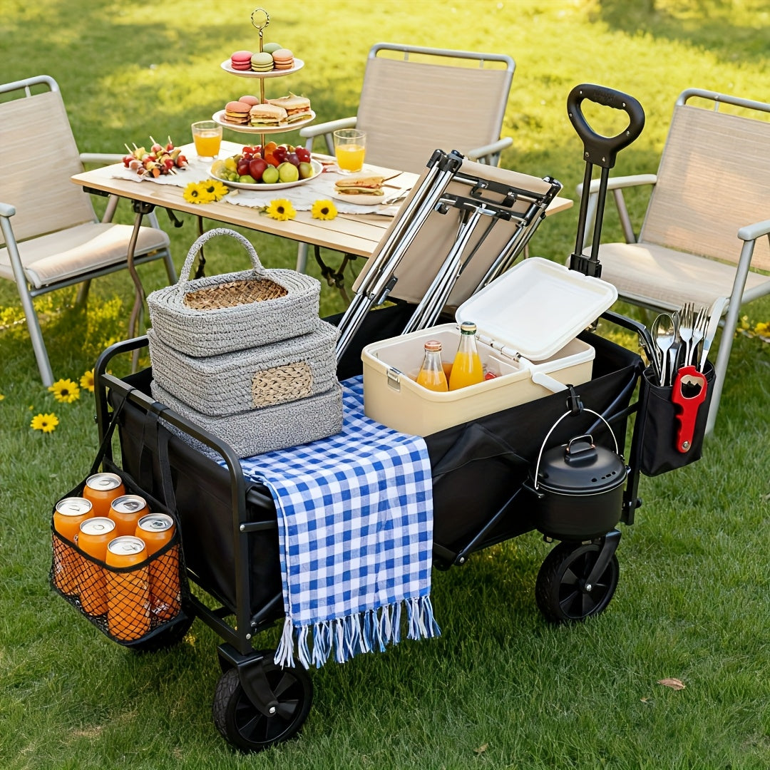 Picnic setup with a cart, table, chairs, and food on a grassy area.